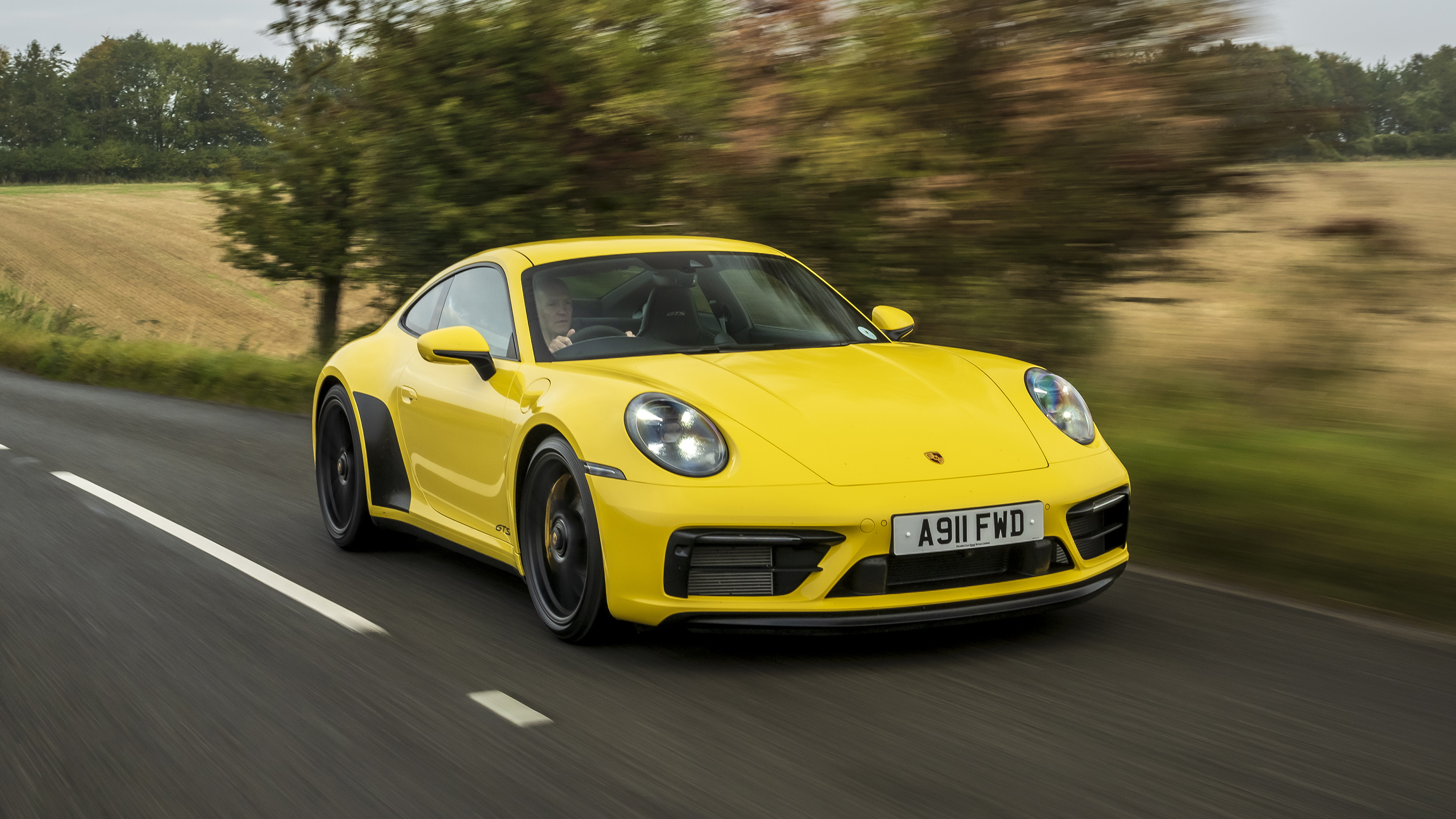 Porsche 911 Carrera 4 GTS coupe yellow front tracking