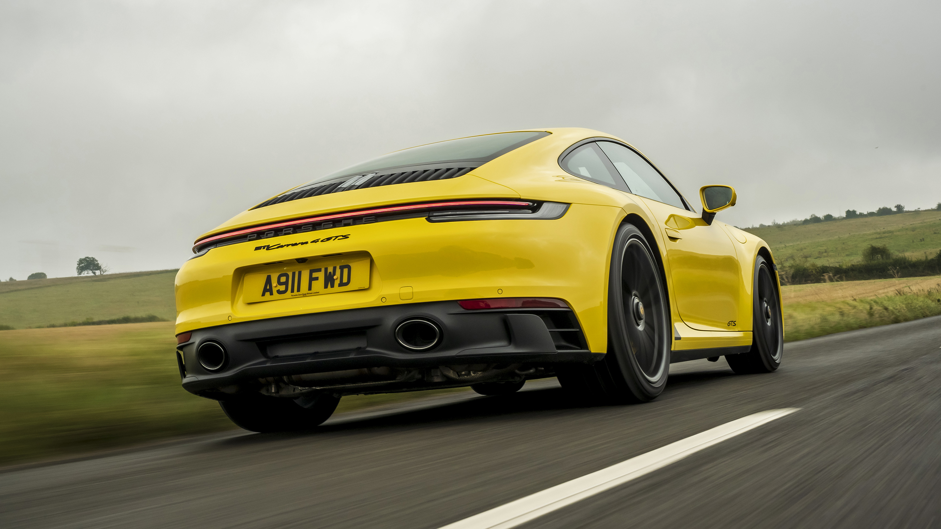 Porsche 911 Carrera 4 GTS coupe yellow rear tracking