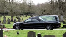 Ford Mustang Mach-E-based hearse driving shot through a cemetery