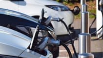 A close up shot of electric vehicles in a line receiving a charge with the cable plugged in