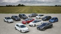 A group of 11 electric vehicles shot on tarmac at an airbase with a field in the background