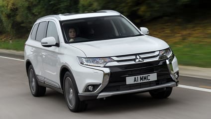 Driving shot of a white Mitsubishi Outlander PHEV taken from driver's side front