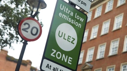 Close up shot of a green ULEZ boundary sign next to a 20mph limit sign