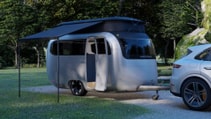 Airstream Porsche travel trailer in campsite with awning up