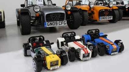 Three Lego models sitting in front of full sized Caterhams