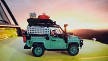 New Lego model, the Classic Land Rover Defender 90, sits atop a real Defender with the sunset behind