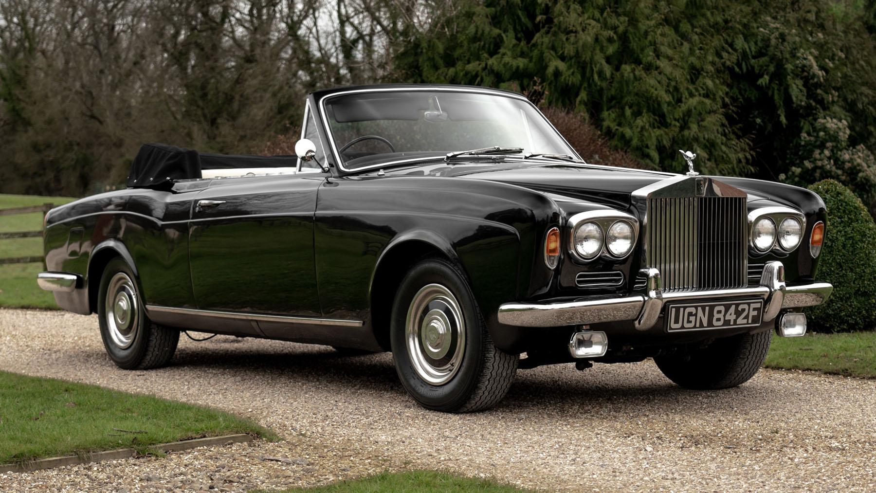 Gleaming black Rolls-Royce Silver Shadow parked on a gravel drive