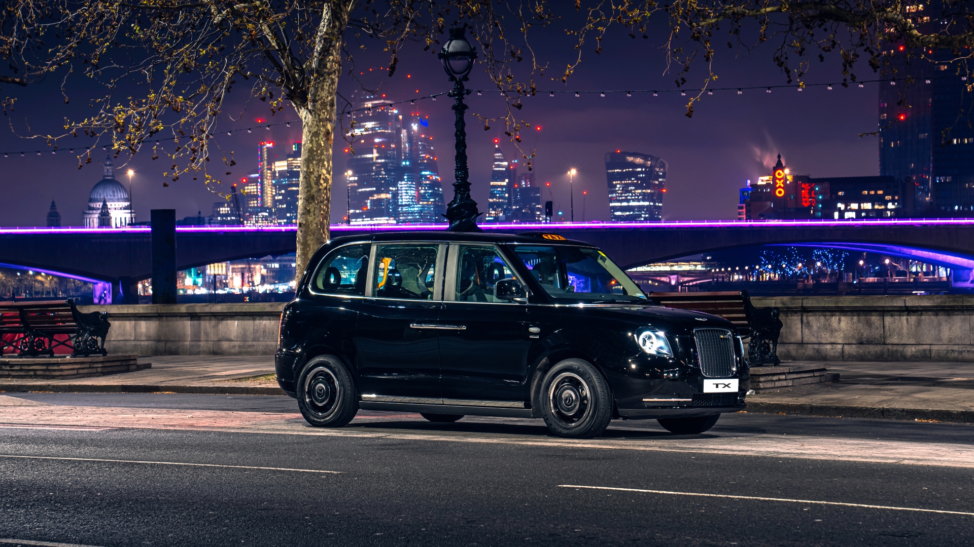 Driving shot of LEVC TX on Embankment alongside river Thames at night with OXO tower in distance