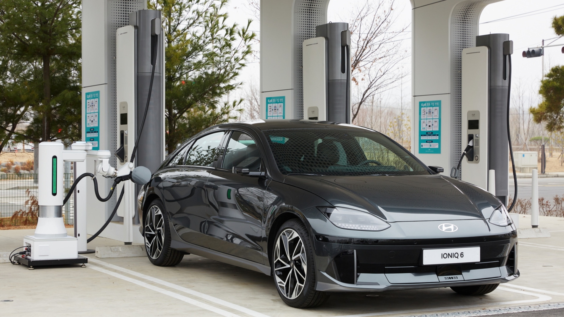 Hyundai IONIQ 6 parked at a charging hub with a robot charger connecting the cable to the car without humans