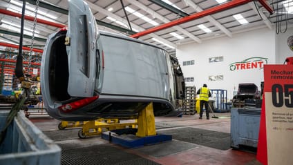 Stage five of recycling process showing car tilted on side to remove engine