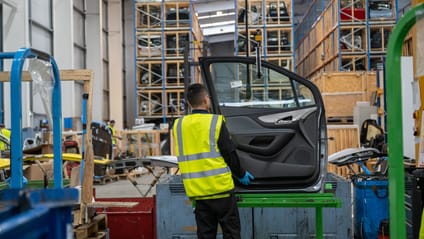 Warehouse worker handling secondhand car door wearing hi vis vest