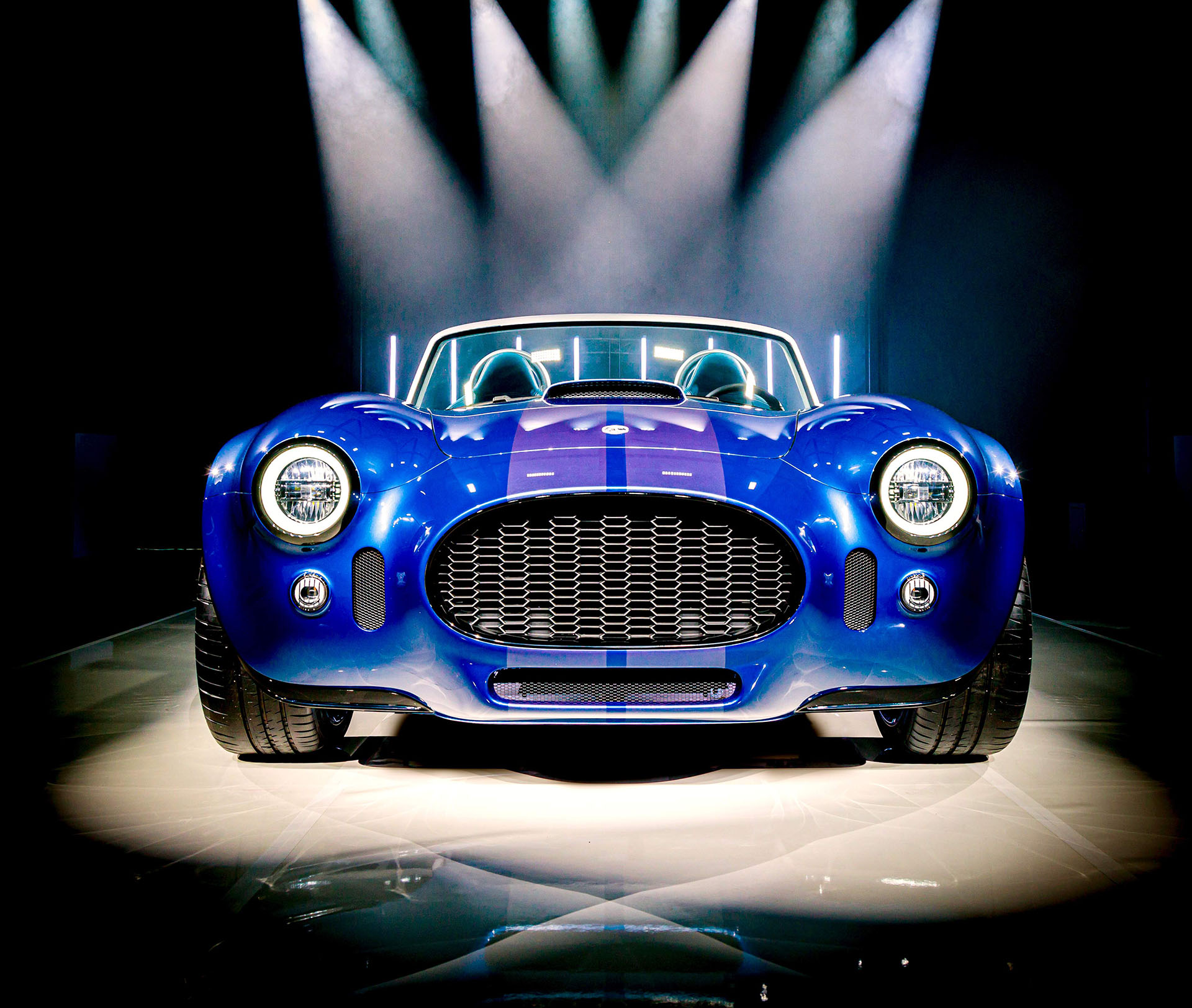 2024 AC Cobra GT Roadster in front facing studio shot with multiple spotlights pointing at it