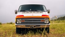 A 1977 Dodge Tradesman camper van  on grassy meadow, front on shot
