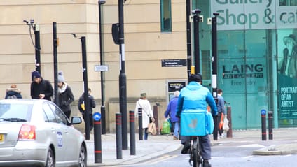 Cyclist riding through a city with a taxi indicating to pull out to the left of them