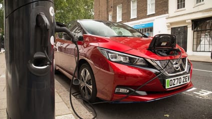 Shot of Nissan Leaf charging on street, charging post in foreground