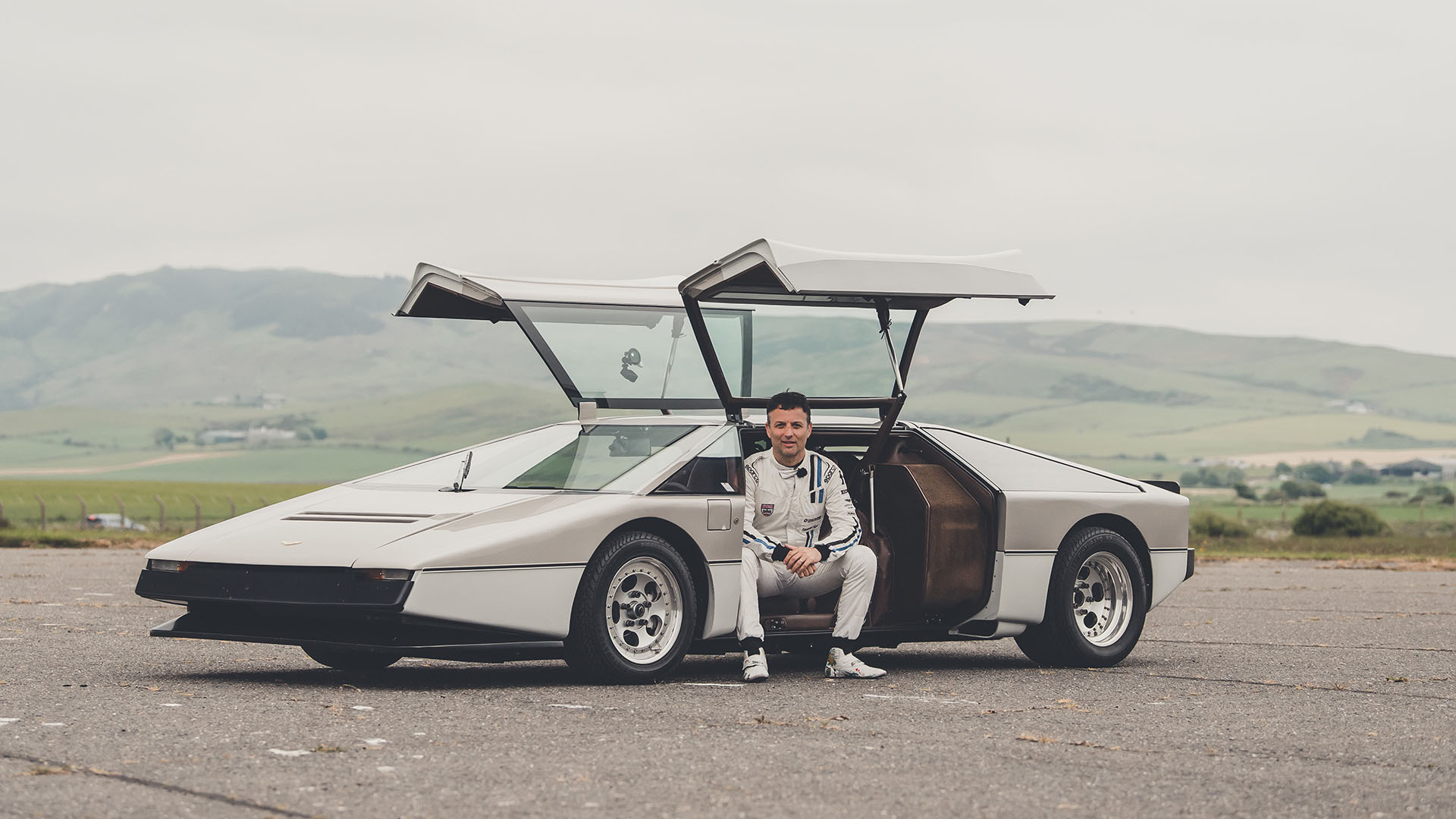 Darren Turner sits on the cill of the restored Aston Martin Bulldog