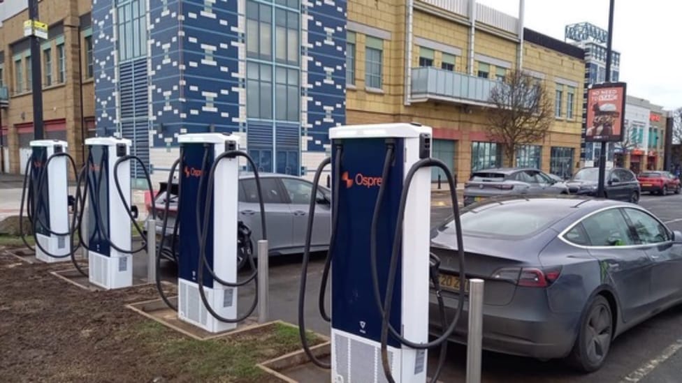 Tesla charging at a bank of Osprey charging devices in retail park