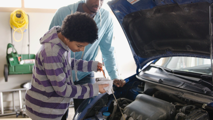 Two people inspecting the engine of a car