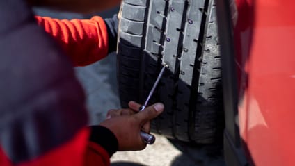 Someone trying to remove a nail stuck in a car tyre