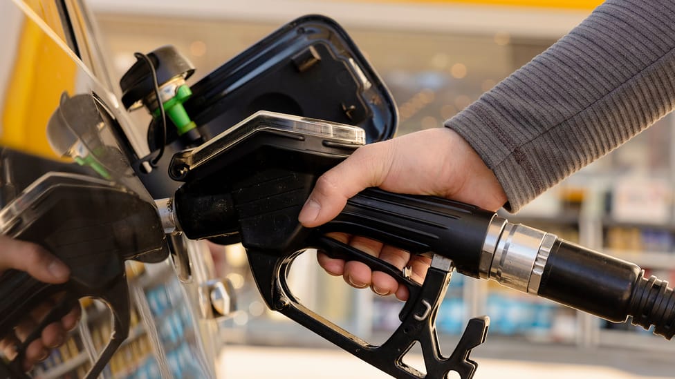 Man's hand holding a petrol pump in a car fuel tank