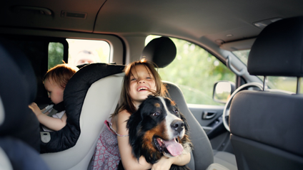 Two children and a dog in a car