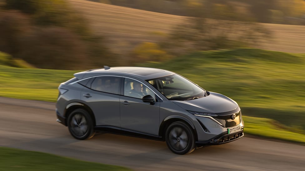 Nissan Ariya driving shot with blurry sun-drenched fields in background