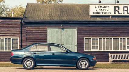 1995 BMW 5 Series in side profile shot with old-school garage backdrop