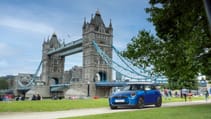 Blue Mini Cooper Electric parked in More London with Tower Bridge in backdrop, static shot