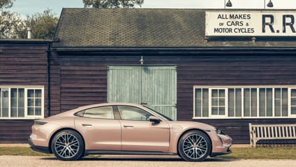 Taycan in side profile shot with old-school garage backdrop