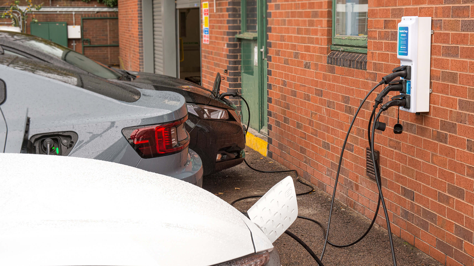 Three cars connected to a charge point on a wall