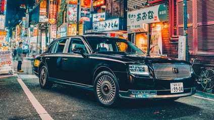 Static shot of Toyota Century on Tokyo street with neon illumination in backdrop