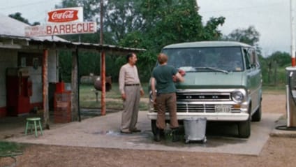 1972 Ford Club Wagon parked at a rural gas station in the US getting a clean