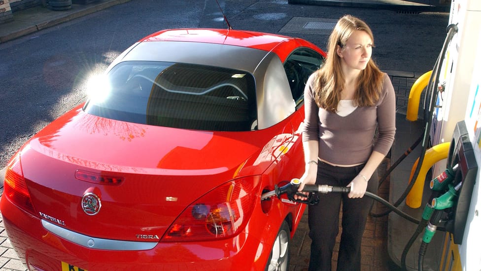 Woman using fuel pump, high angled shot