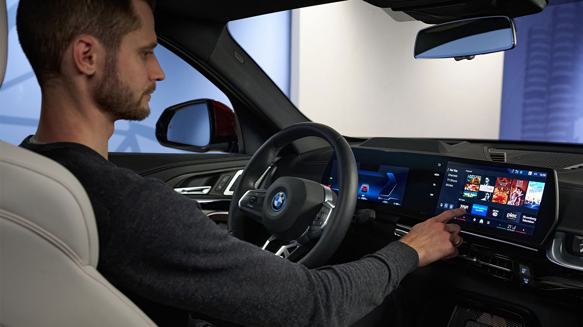 Man sitting in drivers seat selecting with pointed finger something on BMW touchscreen