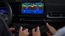 Front passengers in BMW using gaming controllers to play game on centre display screen