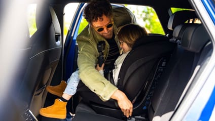 A dad securing his child's car seat 