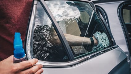 Someone wiping the interior window of a car