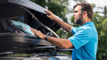 Someone packing an item into a car roof box 