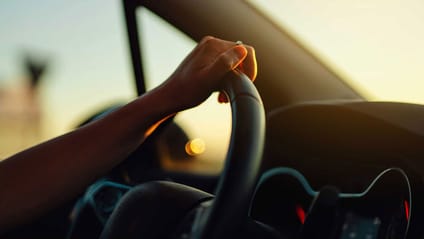 Someone holding on to a car steering wheel