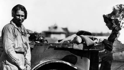 Black and white shot of Claerenore Stinnes standing next to a car