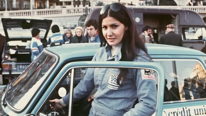 Michele Mouton climbing into a car and looking directly at the camera