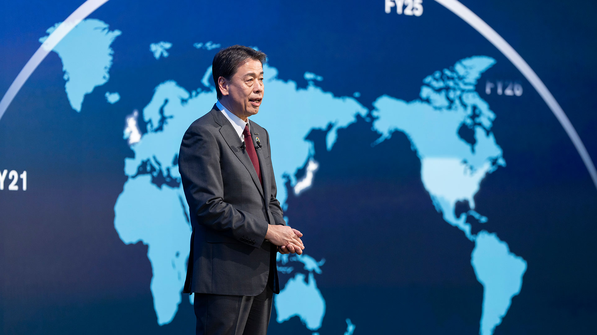 Nissan CEO Makoto Uchida pictured on stage in front of a graphic of the globe