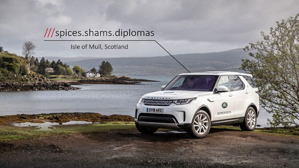 White Land Rover Discover is parked on edge of land in Isle of Mull, with scenic sea backdrop. Graphic overlaid to denote three words used in What3Words mapping tool