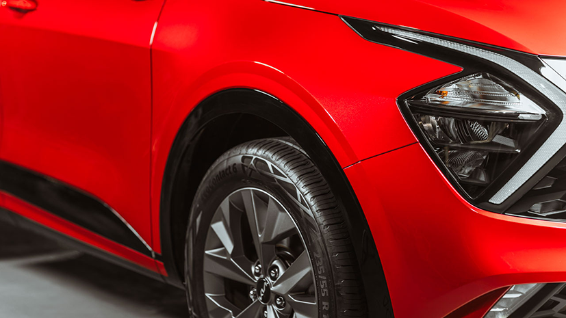 Close up shot of a headlight and wheel of a red car 