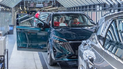 Three Nissan technicians carry out final checks in car under bright illumination