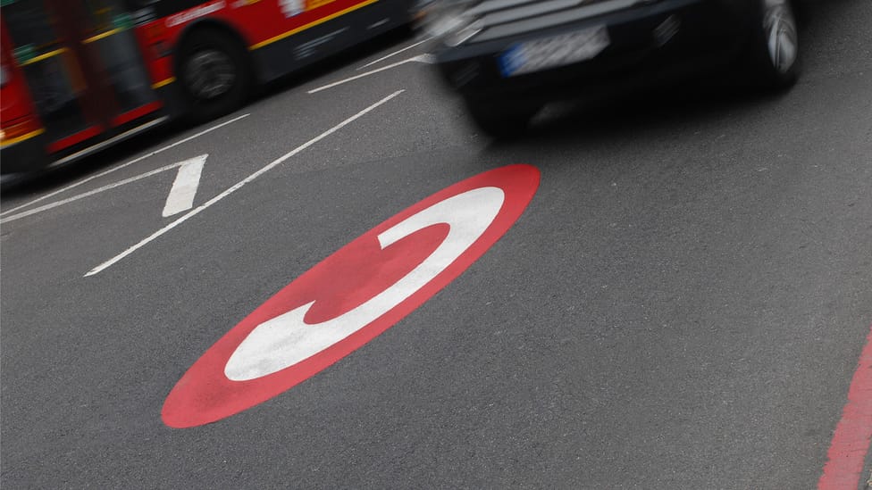 Congestion charge icon on road in London about to driven over by Range Rover