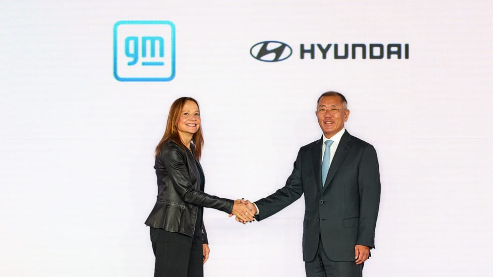 Mary Barra and Euisun Chung shaking hands in front of GM and Hyundai graphics