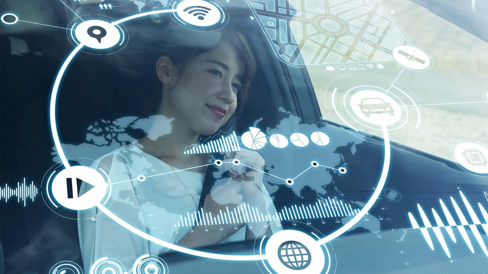 Asian woman sits in car with graphics overlaid on windscreen showing connected car icons