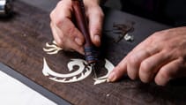 Close up of a person working on the in-laid dragon marquetry on the Rolls Royce Phantom Dragon one-off variant