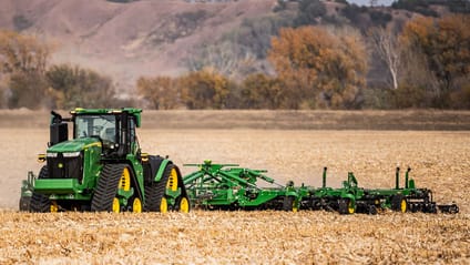 Autonomous tractor working in a field in John Deere's green and yellow brand colours